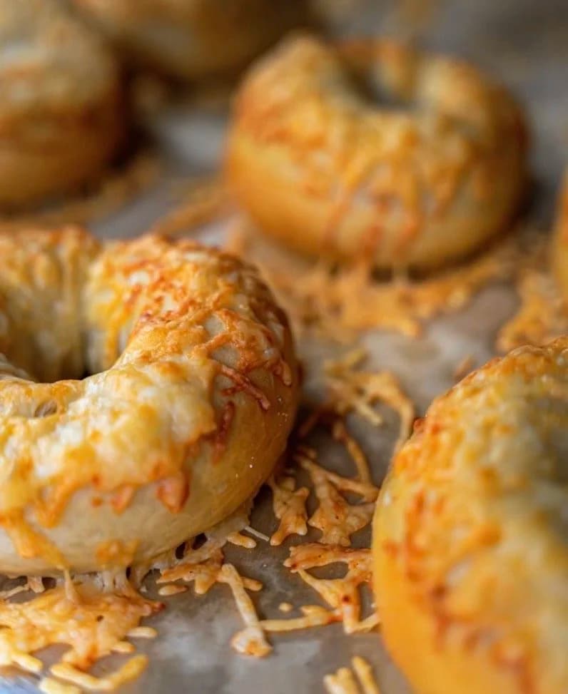 A close-up of Dan's Bagels Asiago bagels with crispy baked-on cheese edges