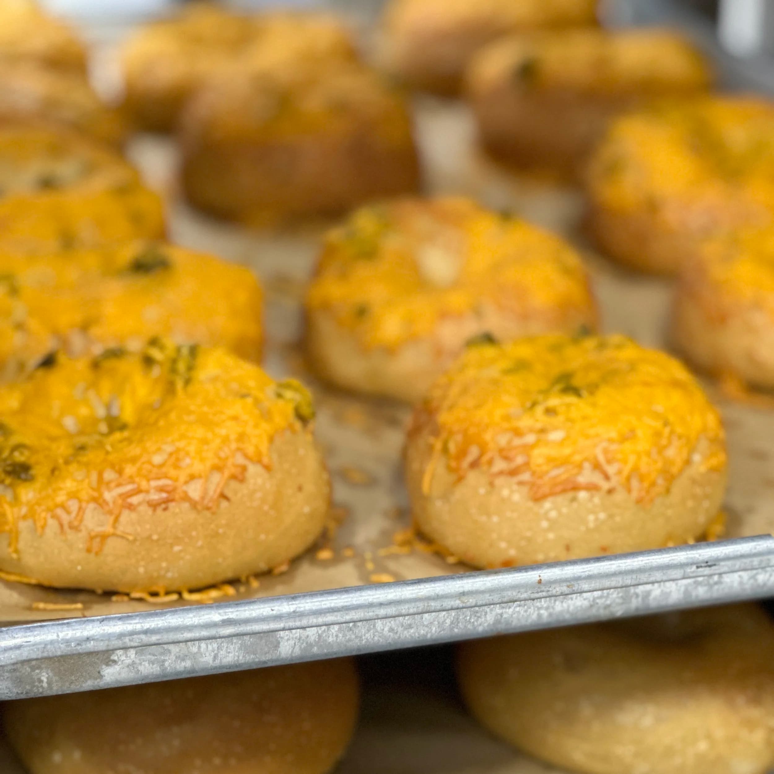 Jalapeño cheddar bagels topped with cheese and sliced jalapeños
