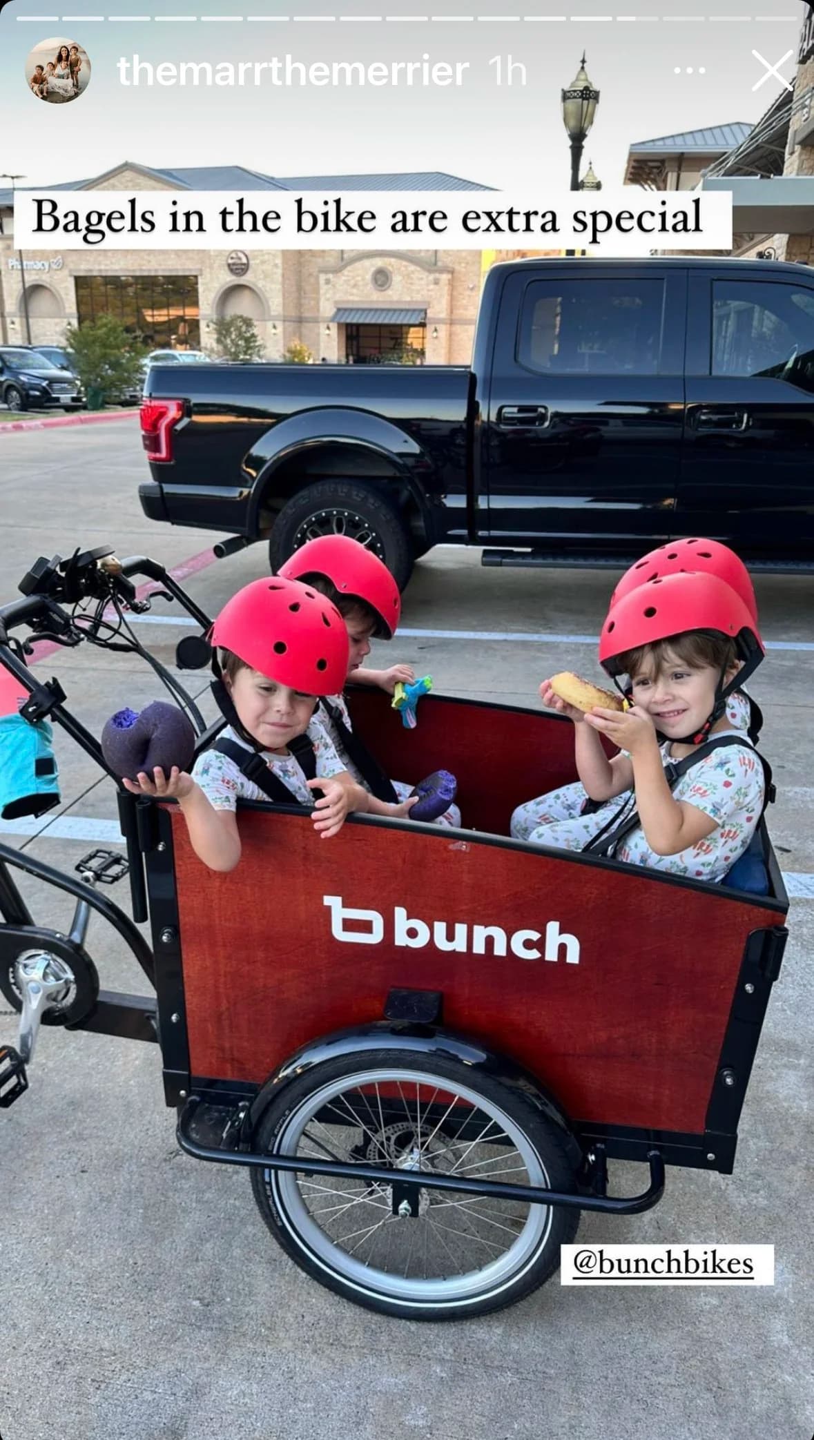 Two kids in a bunch bike cargo bike eating Dan's Bagels