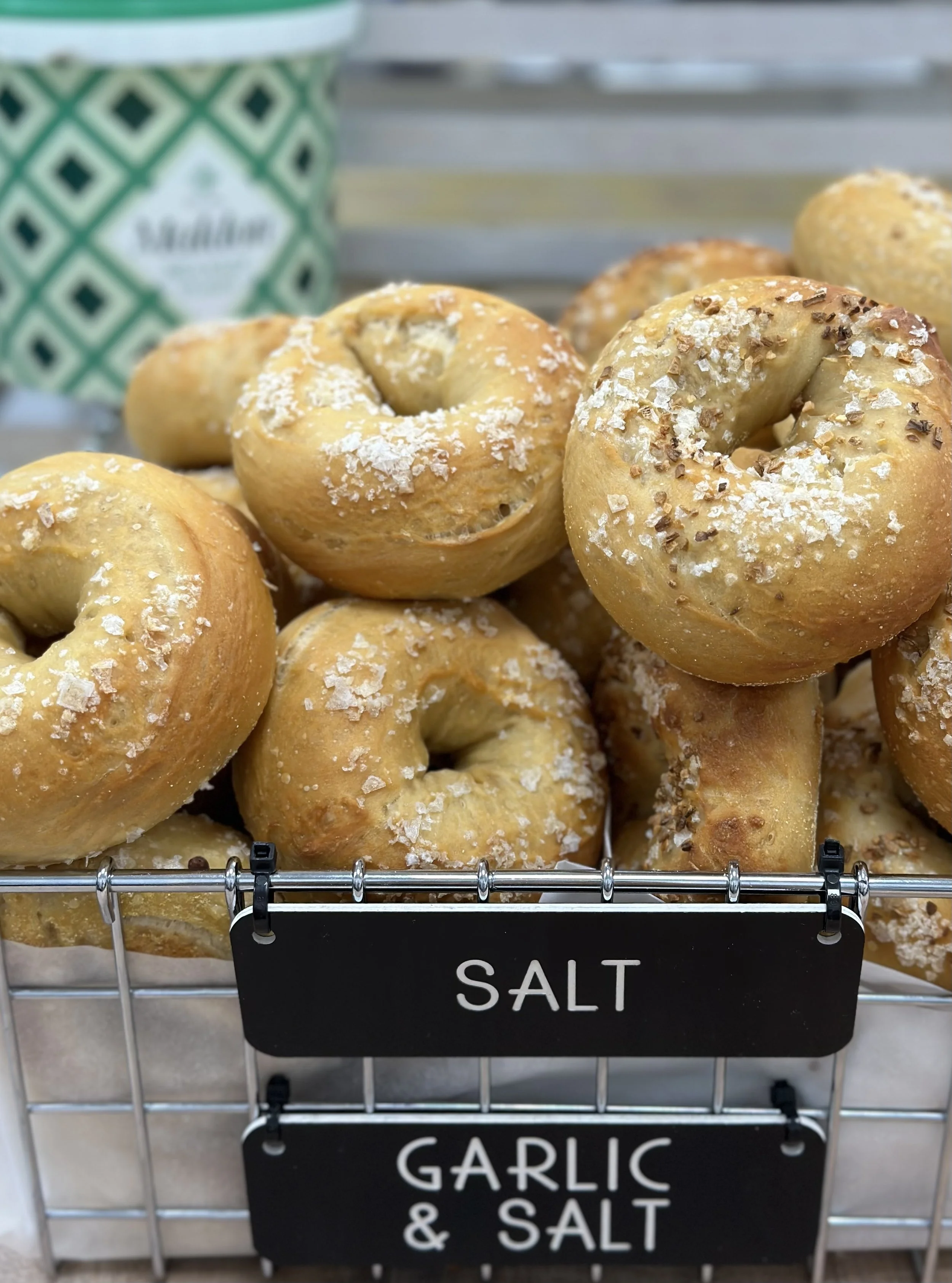 A wire basket of Dan's Bagels salt bagels with chalkboard label